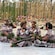 Four Fijian women wearing a traditional dress and headpiece sitting on the floor
